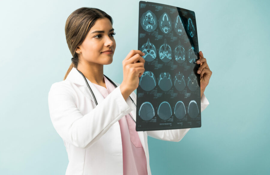 Beautiful female doctor examining xray while standing in studio